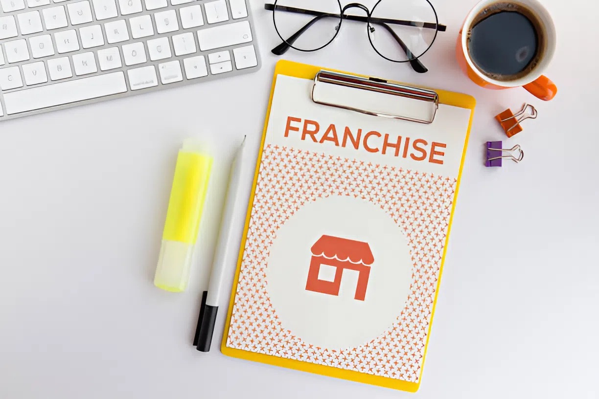 Franchise requirement in the document on a clipboard beside office supplies